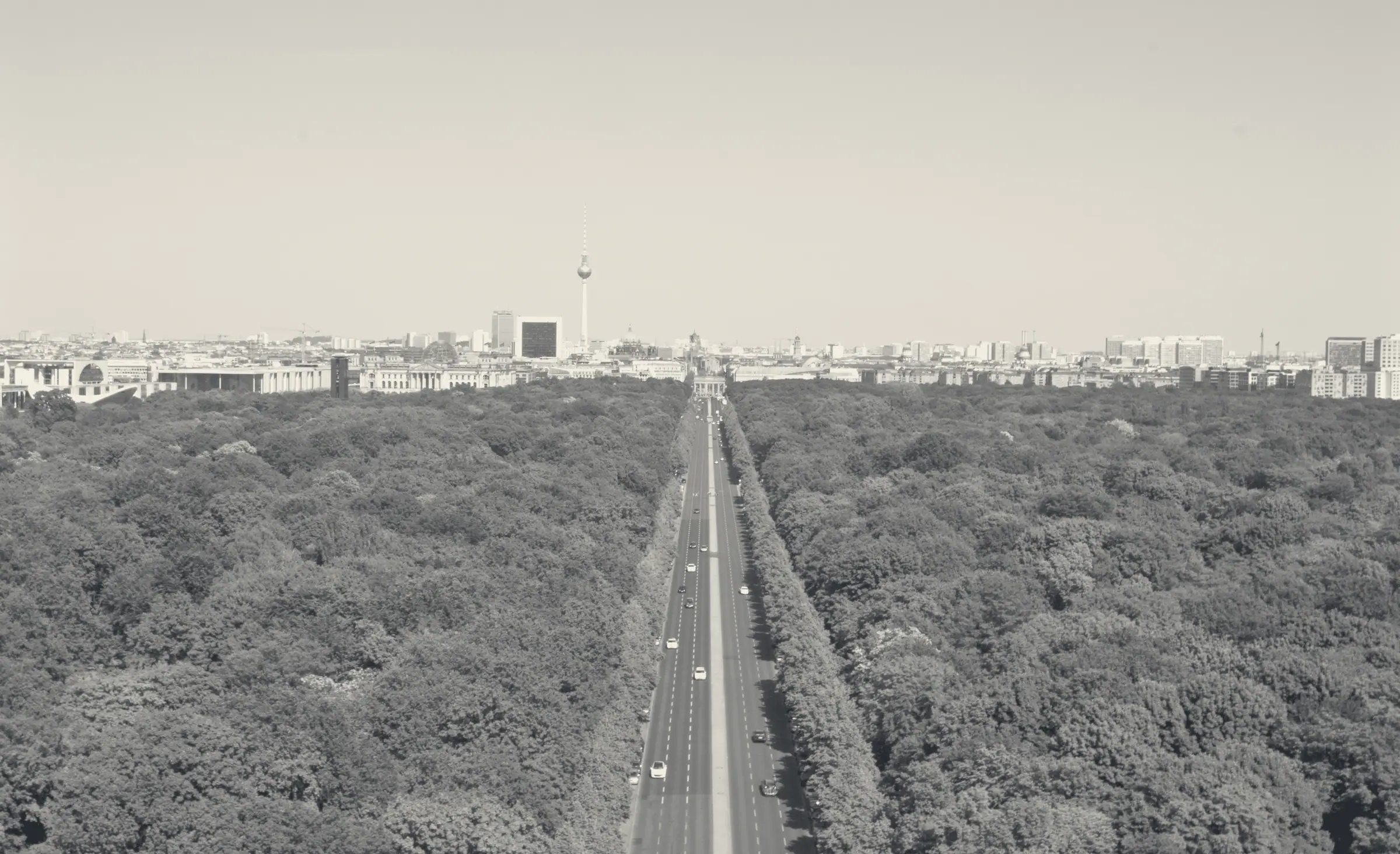 Die Strasse des 17. Juni führt schnurgerade durch den Tiergarten auf das Brandenburger Tor zu, am Horizont der Fernsehturm. Foto in die Farben der Seite umgerechnet.